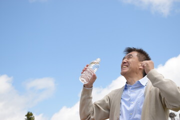 伸びをしながら水分補給をする元気なシニア男性