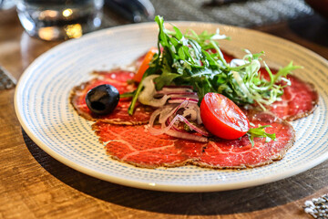 Beef carpaccio with arugula and cherry tomato garnish