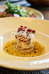 Seared scallop with microgreens and onion garnish