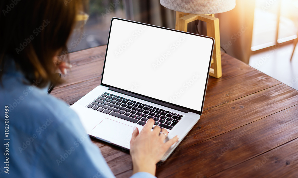 Wall mural mockup image of a woman using laptop with blank screen on wooden table