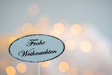 Soft-drawn Christmas card with bokeh effects in the background and a sign with the German inscription 