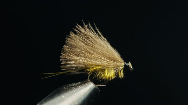 Handmade fishing fly in the vice on the solid studio background
