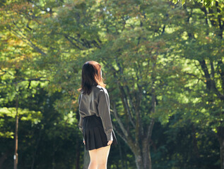 夏の公園でゆっくり散歩する一人の女子高校生の姿