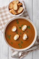 Provencal traditional fish soup puree Soupe de Poisson served with croutons and aioli sauce closeup on the bowl on the wooden table. Vertical top view from above