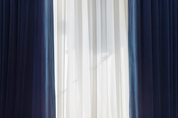 Obraz premium Curtains hang on the window in the room through which sunlight passes