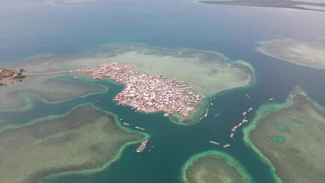Aerial view of a fishing village on the world most populous island, surrounded by blue seas and coral reefs in Bungin Island, Sumbawa NTB, Indonesia.