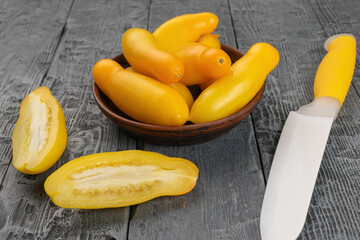 Fresh Yellow Tomatoes on Rustic Wood with Knife: Vibrant Harvest in Rustic Kitchen Setting
