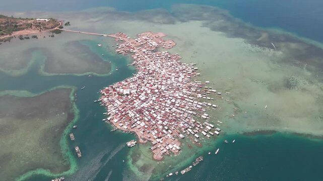 Aerial view of crowded fishing village with boats and houses by the ocean, Bungin Island, Sumbawa NTB, Indonesia.