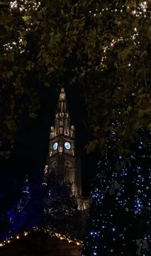 Clock tower at the Town Hall in Vienna, Austria and trees in Christmas lights.
