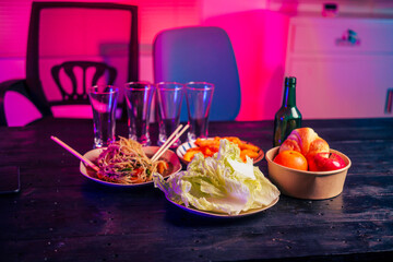 A beer glass and various food and drink items are placed on the table in a party room. The space is empty, setting the scene for an upcoming gathering or celebration