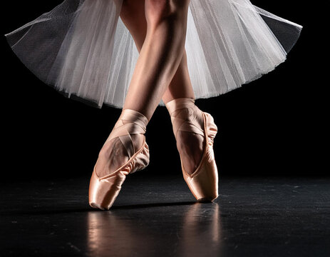 close-up de unas piernas de una bailarina de ballet bailando de puntillas sobre fondo negro