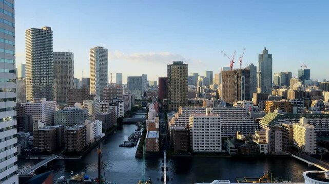 Tokyo skyline with tall buildings and waterways under a clear blue sky, aerial view