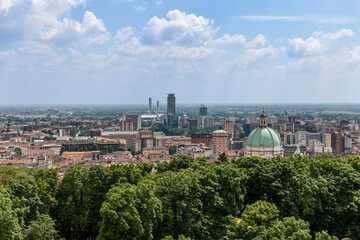 Fototapeta premium Brescia Duomo dome rises above the historic city center tiled rooftops with the business district visible in the distance. The scene highlights the city mix of ancient and contemporary structures