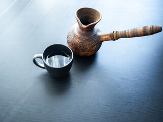 A COFFEE POT AND A CUP ARE ON THE BLACK TABLE