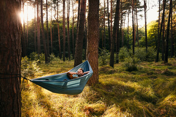 Happy man lying in hammock in forest