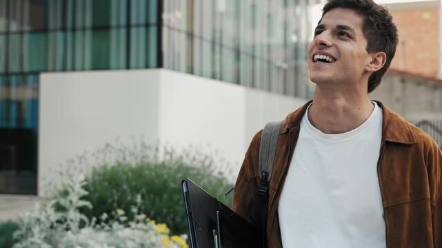 Young inspired man walking on city street - Professional student smiling to camera