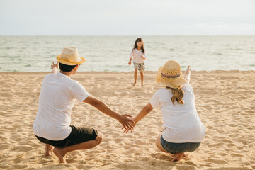 Asian little girl running into family open arms on beach. Happy father and mother welcomes cute daughter enjoying on sandy beach. summer outdoor activities concept