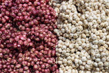 a container full of shallots and white garlic sold in traditional markets