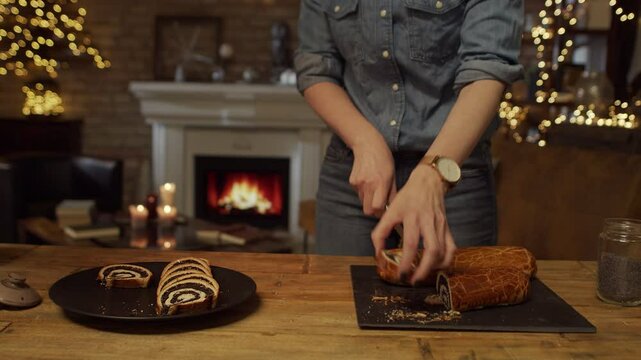 Woman slicing poppy seed roll cake at home at Christmas