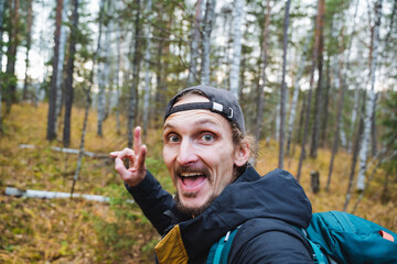 An enthusiastic hiker is joyfully posing in a lush forest while making a peace sign with their hand, surrounded by natures beauty