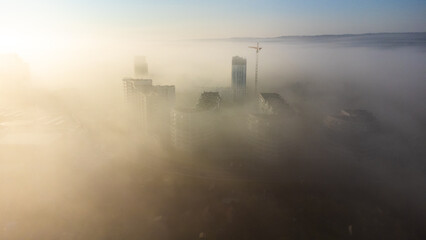 clear sunny morning over the city with tall buildings in the fog © Stepan