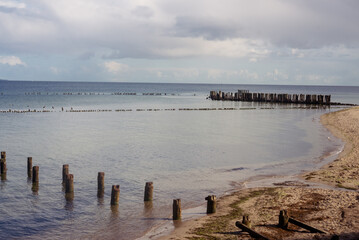 Fototapeta premium the remains of an old wooden bridge into the sea on an autumn evening