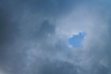 Dramatic dark storms clouds cover the blue sky.