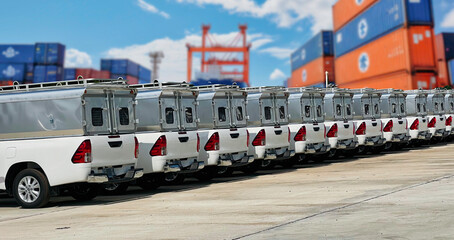 Fleet of cargo trucks in a shipping yard with containers in the background for logistics and...