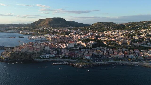 A stunning aerial shot of Pozzuoli, highlighting its scenic coastline and vibrant harbor.The drone captures the ancient Roman ruins, the calm sea, and the natural beauty surrounding the historic city.