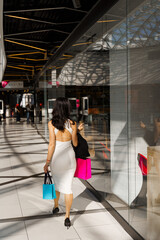 Holiday shopping. Pretty woman is wandering around expensive mall with colorful bags. Shopping with...