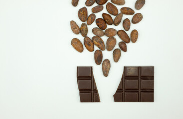 Cocoa beans are poured into the dark broken chocolate. Bean to bar concept. Chocolate production technology. Copy space.