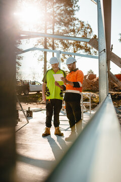 Two construction site managers looking at digital blueprints on worksite