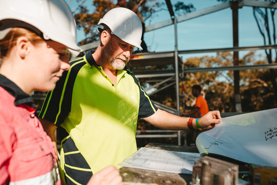 Builders in hardhats looking at the blueprints on construction site