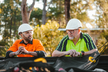 Two builders chatting leaning on ute tray