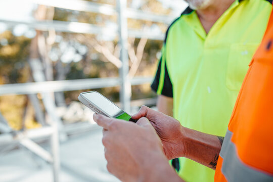 Construction worker holding a mobile device at the construction site.