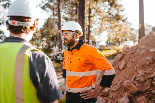 Construction workers standing near the pile of dirt.