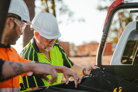Two builders standing next to ute on worksite