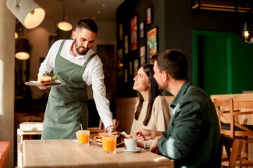Waiter serves delicious vegetarian dishes to cheerful diners in a vibrant café during a sunny...