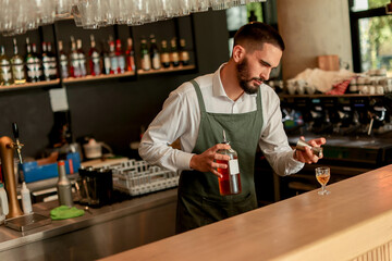 Skilled bartender prepares a cocktail at a stylish bar during a vibrant evening in a bustling city