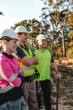 Three construction workers standing on worksite with arms crossed