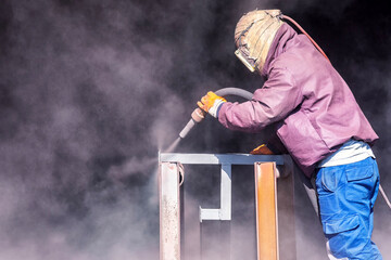 Sandblasting or abrasive blasting. Which is a generic term for the process of smoothing, shaping and cleaning a hard surface by forcing solid particles across that surface at high speeds.