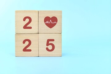 Year 2025 health priority concept. Wooden blocks on blue background with icon.