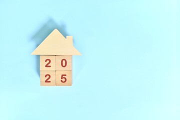 Year 2025 home ownership goal and real estate property investment concept. Wooden blocks on blue...