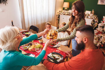 Women bringing food to the table for family Christmas dinner