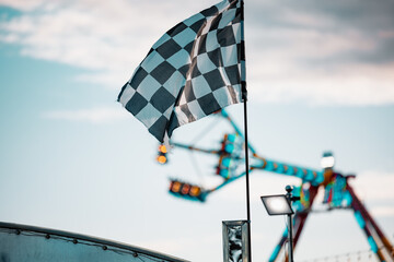 Racing flag at carnival with amusement ride in background