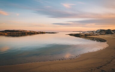 Obraz premium Peaceful sunset cove. Tranquil scene of a sandy shore meeting calm water with a distant rocky island, bathed in the golden light of sunset.