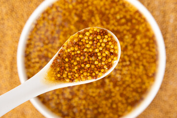 Traditional French Dijon mustard in a spoon on a white background