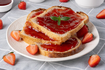 Bread with tasty strawberry jam on grey table