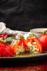 View of open stuffed tomatoes on a plate with mustard, on a wooden table and black background, vertical, with copy space
