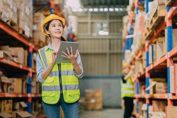 Obraz premium Warehouse workers using a digital tablet while recording inventory. Logistics employees working with warehouse management software in a large distribution centre.
